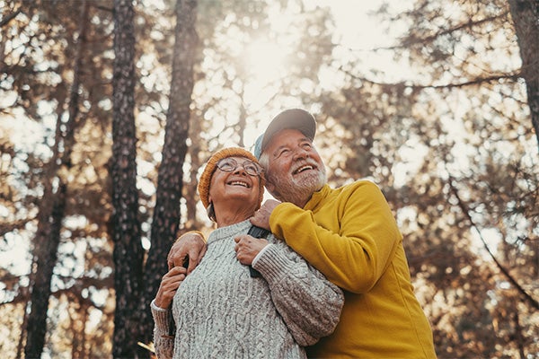Happy older couple in warm clothes enjoying a walk in the woods.