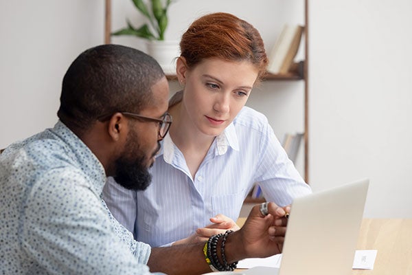 African american man mentors female staff member over computer