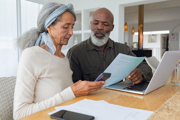 Older black couple goes over their finances in their new modern home with their laptop