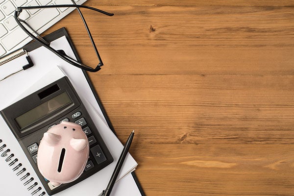 calculator, notebook, clipboard, pen piggybank, and glasses