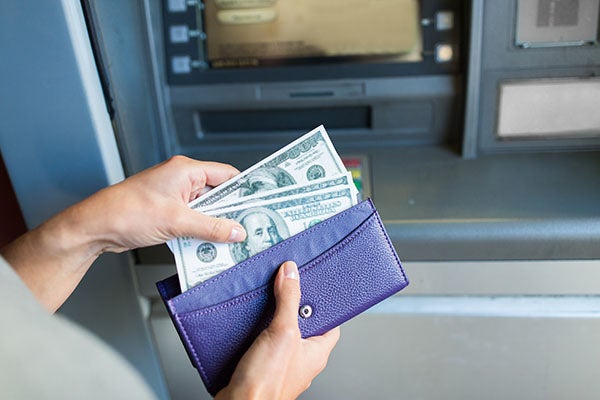 womanputs hundred dollar bills into her wallet from an ATM