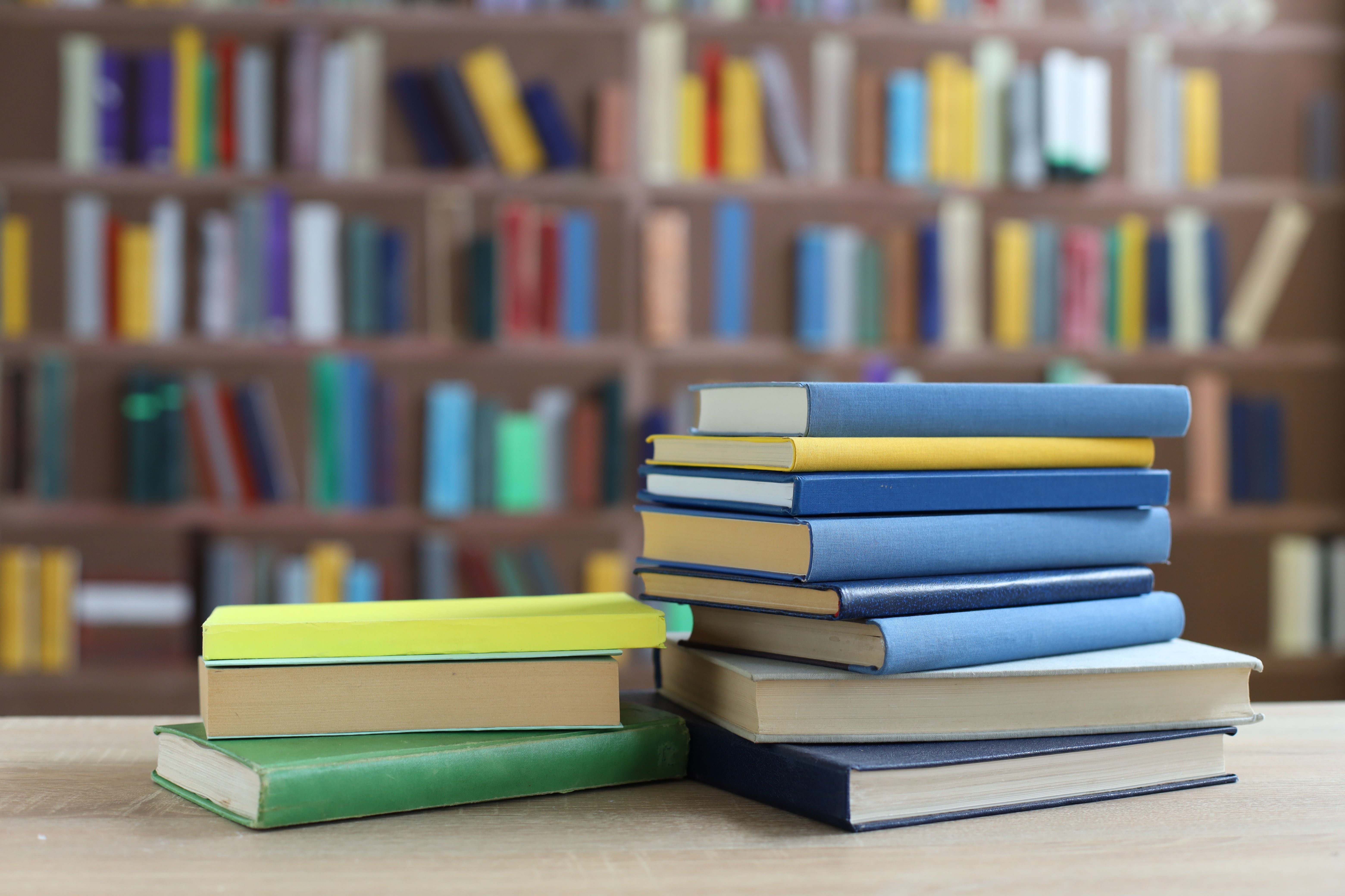 stack of books on wooden table in library