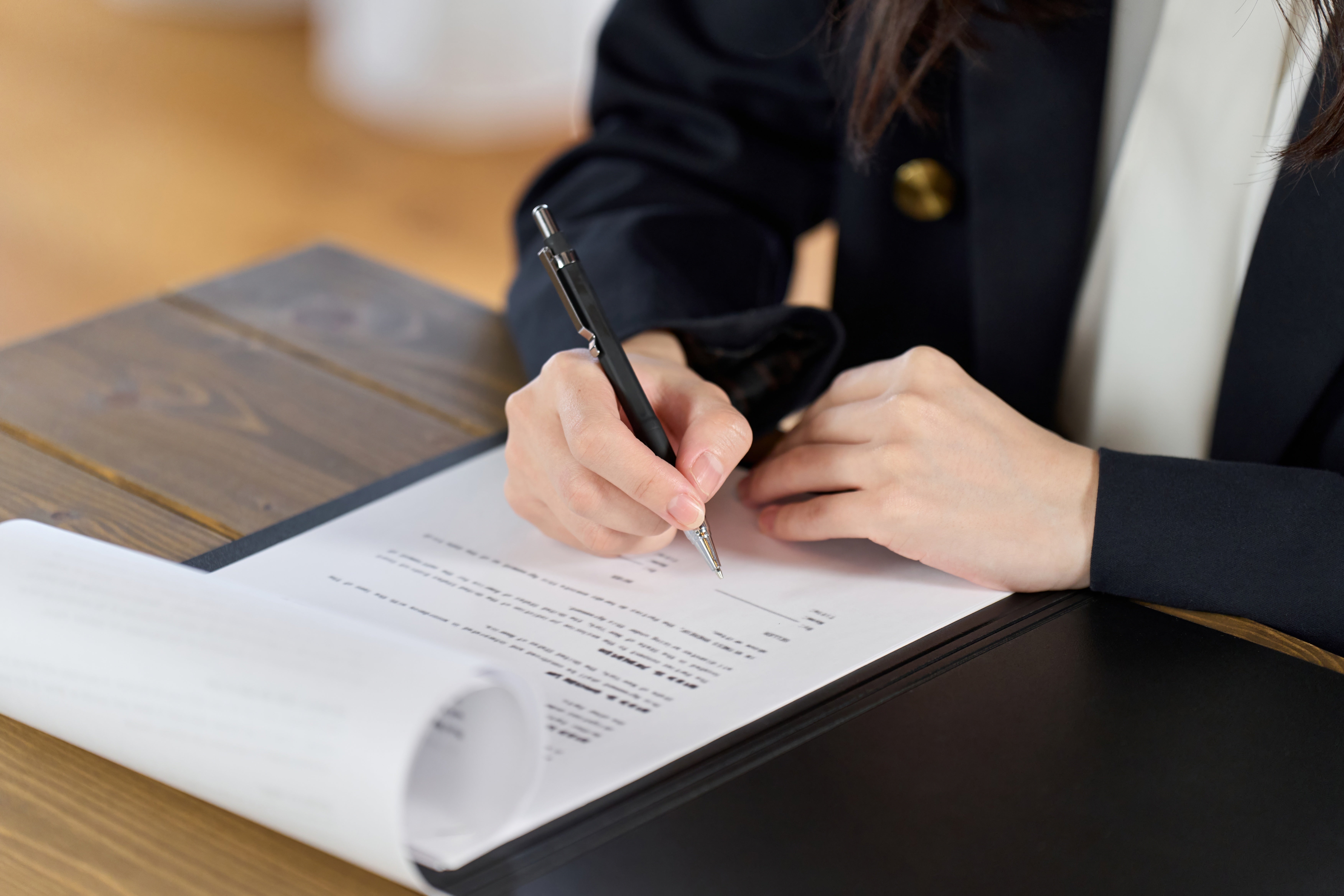 Person signing a contract on a desk