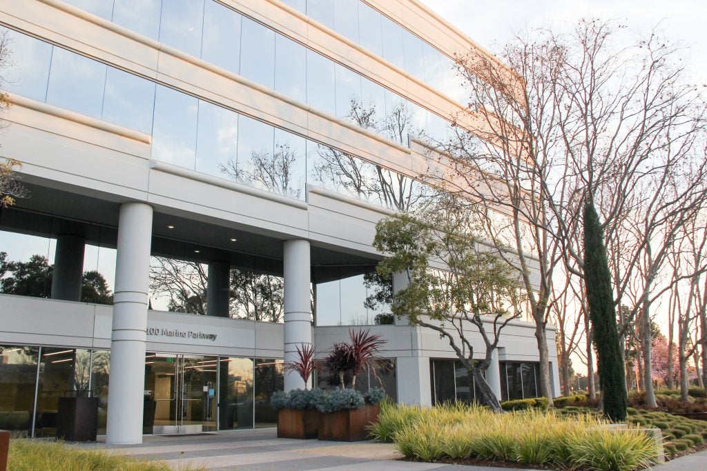 Photo of office building with trees and foliage in front.